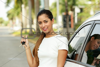 Happy young adult smiling and showing keys of new car