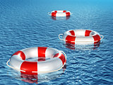 Three lifebuoys, floating on waves