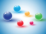 Different colour glass balls on blue background.