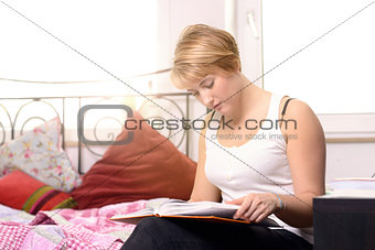 Pretty young student reading in a textbook