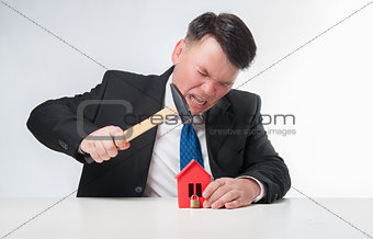 Angry men holding hammer over red paper house