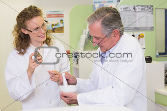 Senior pharmacist mixing a medicine with his colleague