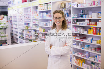 Portrait of a smiling pharmacist  in lab coat with arms crossed