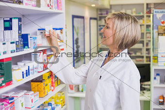 Pharmacist taking medicine from shelf