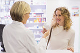 Smiling pharmacist and customer discussing a product