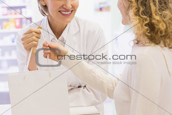Pharmacist and costumer holding paper bag