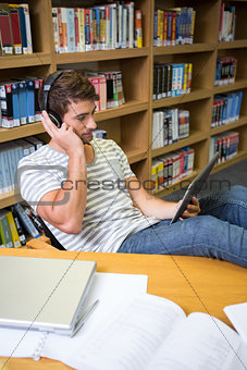 Student listening music in the library with tablet