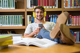Student listening music in the library with smartphone