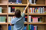 Student picking a book from shelf in library