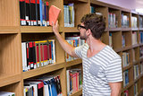 Student picking a book from shelf in library