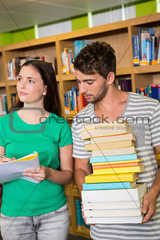 Students with pile of books in the library