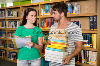 Students with pile of books in the library