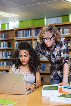 Student getting help from classmate in library