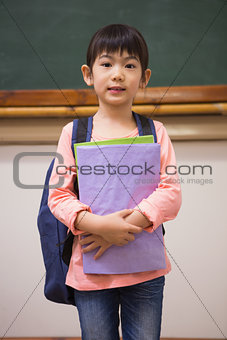 Cute pupil looking at camera holding notepad