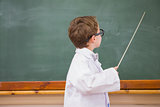 Cute pupil holding stick and pointing blackboard