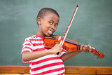 Happy pupil playing violin in classroom