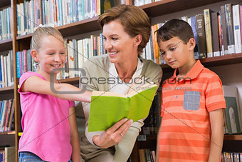 Teacher reading book with pupils at library