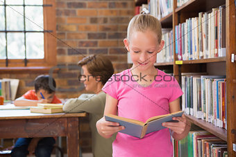 Cute pupil reading in library