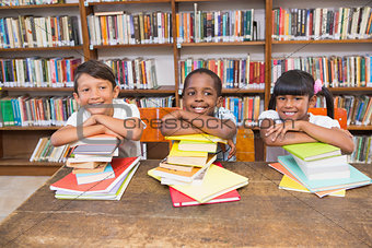 Cute pupils smiling at camera at the library