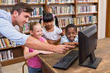 Teacher and pupils using computer at library