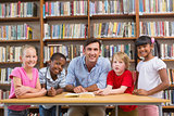 Teacher and pupils smiling at camera at library