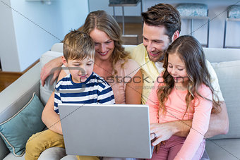 Happy family on the couch together using laptop