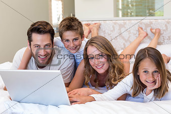 Happy family on the bed using laptop