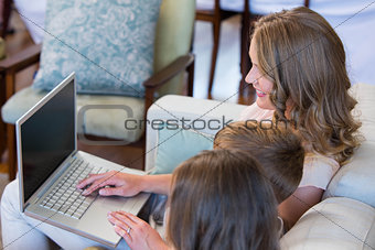 Mother and children using laptop on couch
