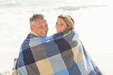 Happy couple wrapped up in blanket