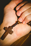 Hand holding wooden rosary beads