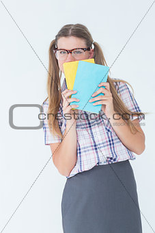 Geeky hipster hiding her face behind notepad