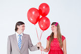Smiling geeky couple holding red balloons
