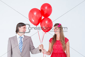 Smiling geeky couple holding red balloons