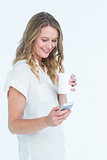Woman using smartphone while holding coffee