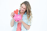 Smiling woman holding piggy bank and red heart