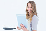 Smiling woman holding frying pan and tablet pc