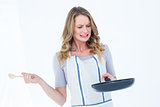 Woman holding frying pan and wooden spoon