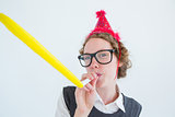 Geeky hipster wearing a party hat wig blowing party horn