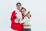 Geeky hipster in santa costume hugging his girlfriend