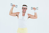 Geeky hipster lifting dumbbells in sportswear