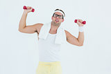 Geeky hipster lifting dumbbells in sportswear