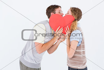Geeky hipster couple kissing behind heart card