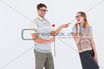 Geeky hipster holding rose and pointing his girlfriend
