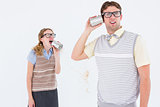 Geeky hipster couple speaking with tin can phone