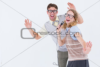 Geeky hipster couple singing into a microphone