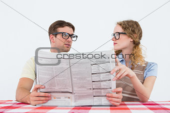 Geeky hipster couple reading newspaper