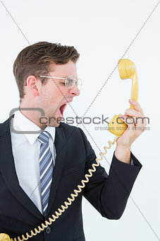 Geeky businessman shouting at telephone