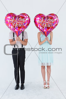 Geeky hipster couple with balloons in front of their head