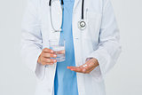 Doctor holding glass of water and pills