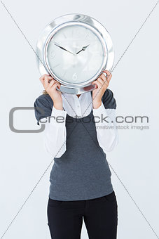Woman holding clock in front of her head